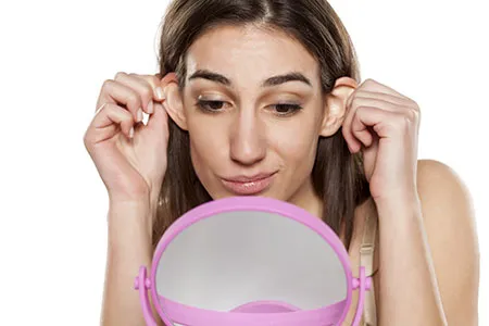 Woman looking at ears in mirror